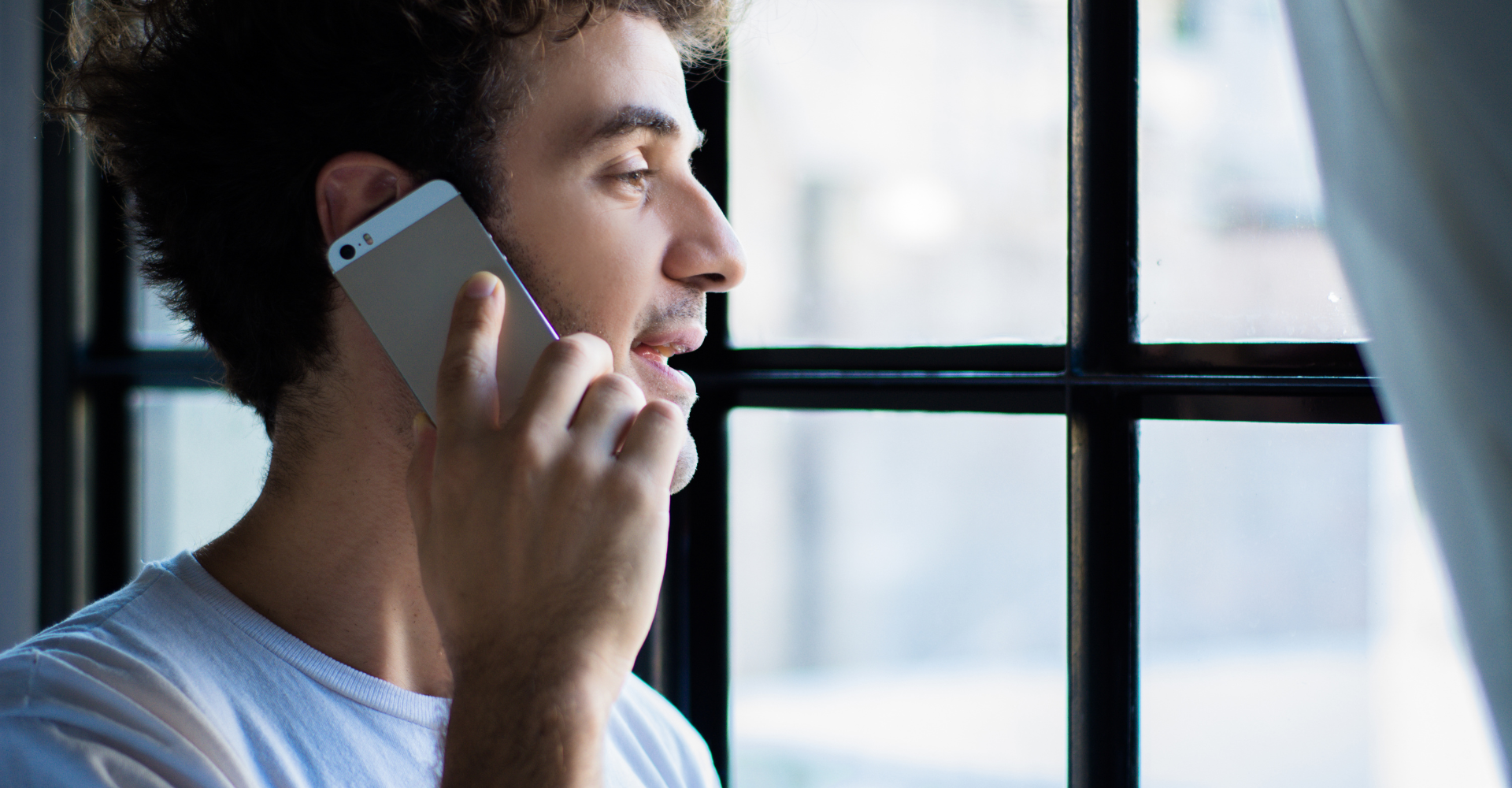 A young man holds his phone up to his ear to speak to a Mosaic Counseling intake specialist to set an appointment and get connected to therapy.