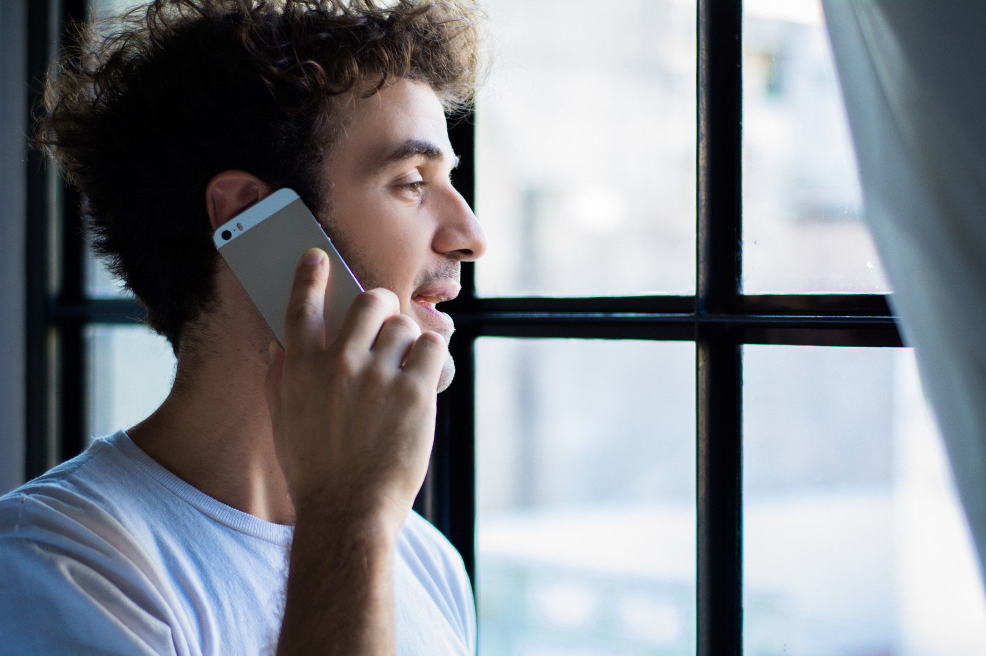 A young man holds his phone up to his ear to speak to a Mosaic Counseling intake specialist to set an appointment and get connected to therapy.